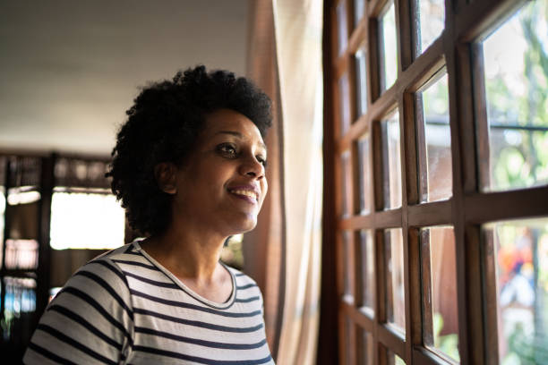 istock Mature woman contemplating, looking through the window 1266837619