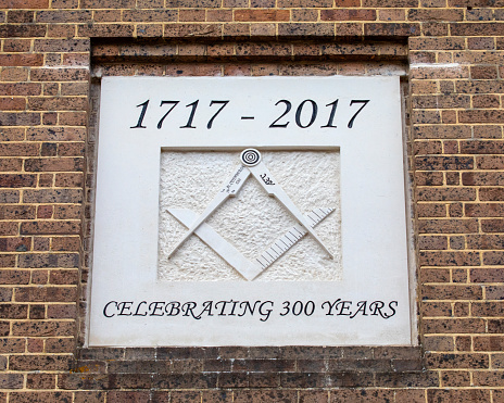 Dorset, UK - August 1st 2020: A sculptured plaque of the logo of the Freemasons displayed on the exterior of Wimborne Masonic Hall in the market town of Wimborne Minster in Dorset, UK.