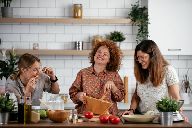 Girlfriends having fun in kitchen. Sisters cooking together..