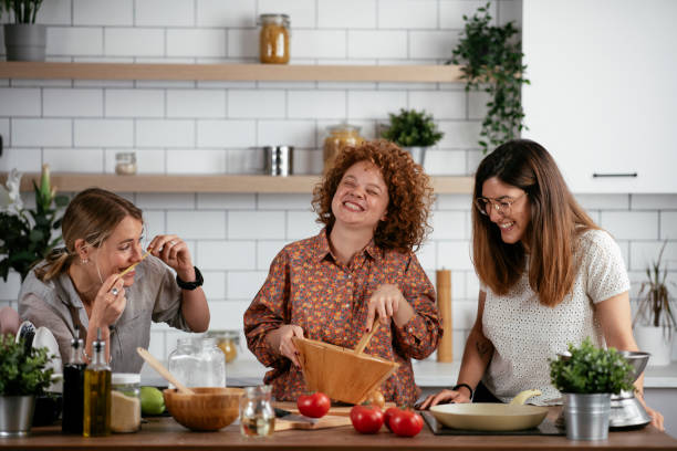 Girlfriends having fun in kitchen. Sisters cooking together.. stock photo