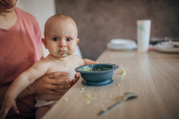 A Little baby eating her dinner and making a mess on his face