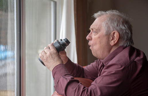 Nosy neighbor looking out of window with shocked expression, holding binoculars