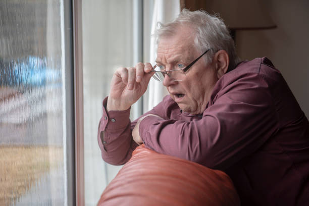 homme aîné choqué regardant par la fenêtre - indiscret photos et images de collection