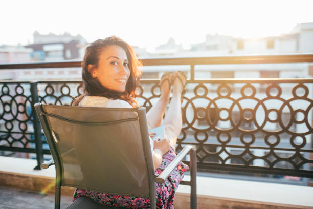 Woman wearing face mask reading book on balcony