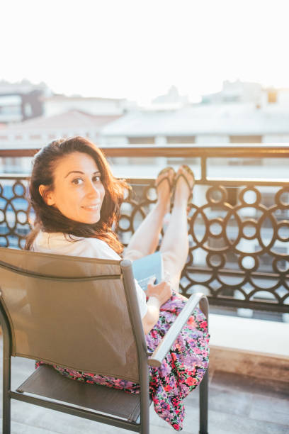 istock Woman reading book on her balcony during the lockdown 1266843660