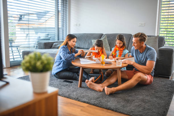 istock Multi-ethnic Family Playing with Paper Airplane Indoors 1266845556