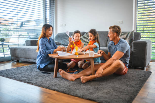 istock Multi-ethnic Family Playing with Paper Airplane Indoors 1266845613