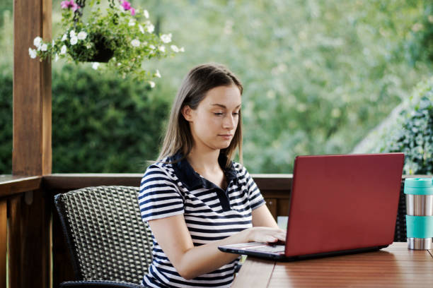 istock Young woman using laptop while sitting outdoor 1266847778