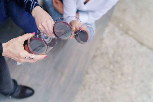 Top view on female hands holding glasses of red wine - copy space friends toasting