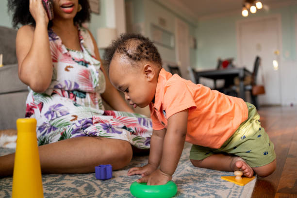 istock Mom playing with her kid while talks on the cell phone 1266851485
