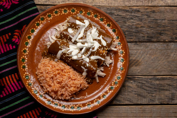istock Mexican chicken enchiladas with mole sauce and rice on wooden background 1266851497