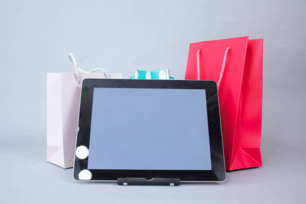 online shopping concept. close-up tablet mockup with white screen with bright gift bags on gray background. - ipad shopping gift retail imagens e fotografias de stock