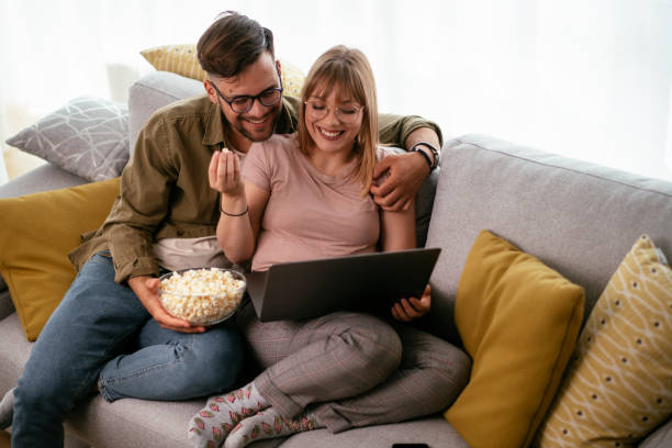 Young couple watching movie on lap top. Young couple watching movie on lap top. Loving couple enjoying at home. sofa bed stock pictures, royalty-free photos & images
