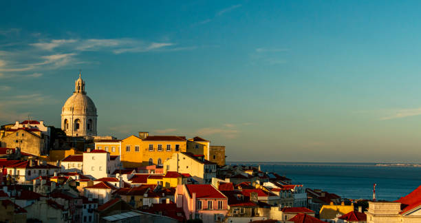 Afternoon in Alfama District, Lisbon Portugal A sunset view of the historic Alfama district of Lisbon, Portugal. Image features the National Pantheon (the white dome overlooking the city), houses, Tagus River and Vasco da Gama bridge. national pantheon lisbon stock pictures, royalty-free photos & images
