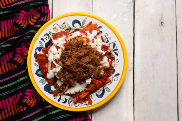 istock Mexican red chilaquiles with chilorio and cheese on white background 1266856955