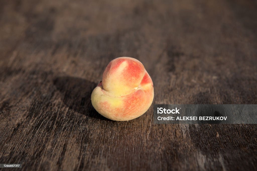 Ugly ripe fresh peach on a vintage wooden background. Selective focus, copy space. Concept - reducing food waste Ugly ripe fresh peach on a vintage wooden background. Selective focus, copy space. Concept - reducing food waste. Imperfection Stock Photo