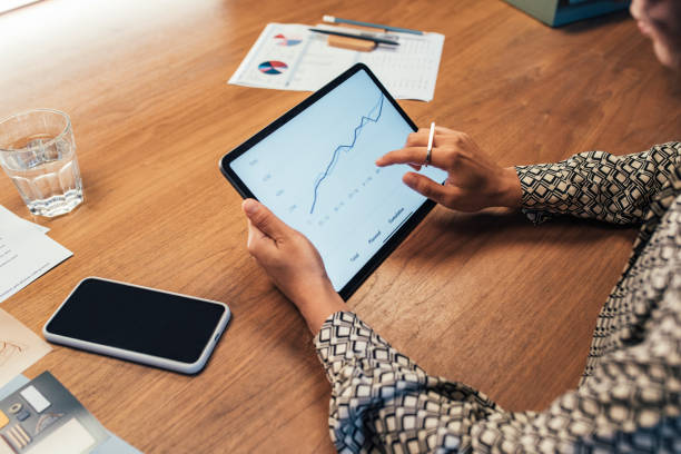 istock Anonymous Businesswoman Analyzing Statistical Business Reports on her Tablet PC at the Office, a Close Up 1266858243