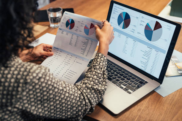 istock Anonymous Businesswoman Analyzing Statistical Business Reports on her Laptop PC at the Office, a Close Up 1266858250