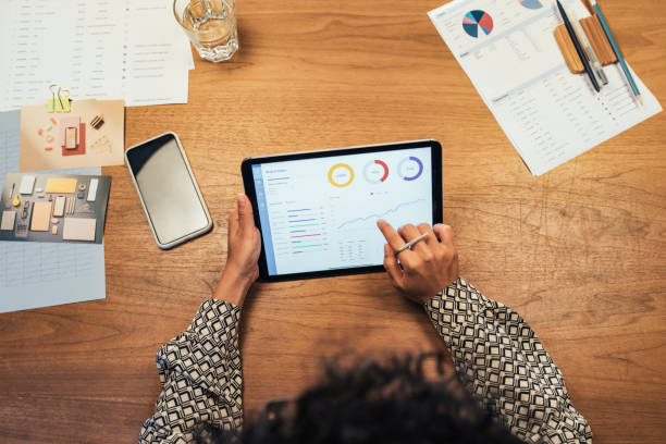 istock Anonymous Businesswoman Analyzing Statistical Business Reports on her Tablet PC at the Office, a Close Up 1266858254