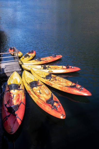 istock seven orange kayaks on a dock placed radially on a blue lake 1266859055