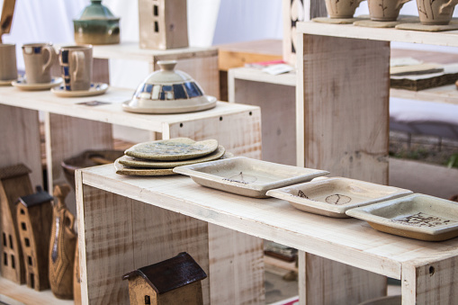 Handcrafted crockery over wooden exhibitor with plates, tea cups and stoneware products