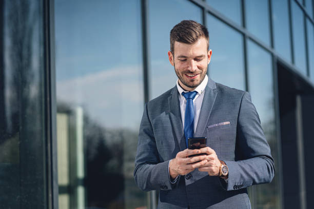 istock Handsome businessman in suit text messaging on a mobile phone 1266862689