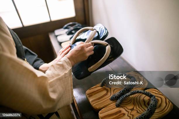 Japanese Woman Picking Up Zori Sandal At The Entrance Of Traditional Japanese Ryokan Hotel Stock Photo - Download Image Now