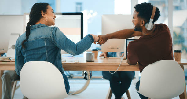 We'll keep on winning as long as we work together Rearview shot of two young designers giving each other a fist bump in an office achievement stock pictures, royalty-free photos & images