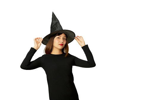 Cute senior woman, with long silver hair, dressed as a witch for Halloween, she is wearing a big witch hat. She is looking at the camera and crooking her finger out at the watcher. Defocused background added to draw the eye to the witches face.