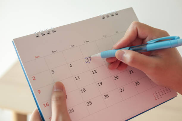 istock Hand with pen mark at 5th on calendar date with blue circle 1266868343