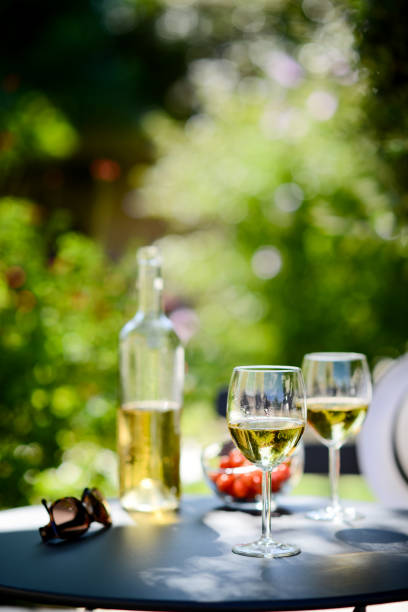 due bicchiere di vino bianco fresco con bottiglia all'aperto nella terrazza del ristorante durante una soleggiata giornata estiva - wine bottle food wine restaurant foto e immagini stock