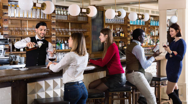istock Barman is servicing young people who are relaxing in bar indoor. 1266872701