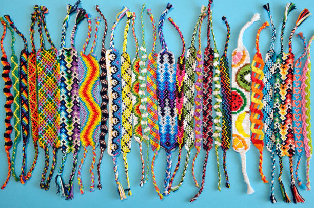 Multi-colored woven friendship bracelets handmade of embroidery bright thread with knots isolated on blue background stock photo