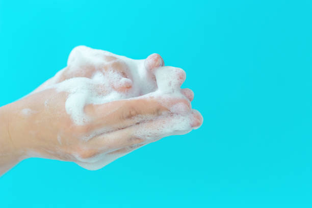 istock The girl washes her hands with foam on blue background, side view 1266881012
