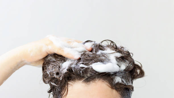 istock A girl washes her hair shampoo on white background with copy space, front view 1266881109