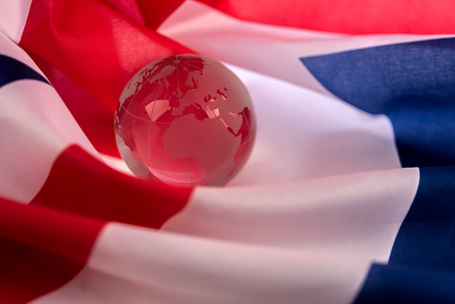 Transparent glass planet Earth wrapped in UK flag.