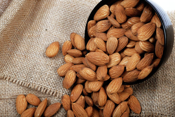 istock Group of almonds inside and outside bowl isolated on white. 1266886297