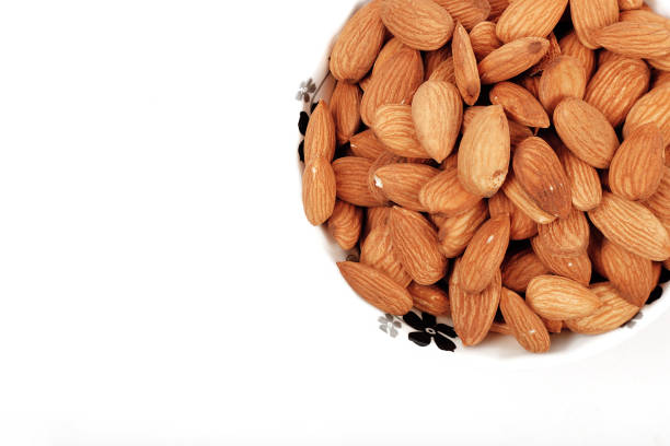 istock Group of almonds inside and outside bowl isolated on white. 1266886902