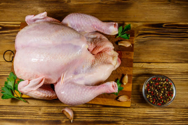 istock Raw whole chicken with spices on a wooden table. Top view 1266902194