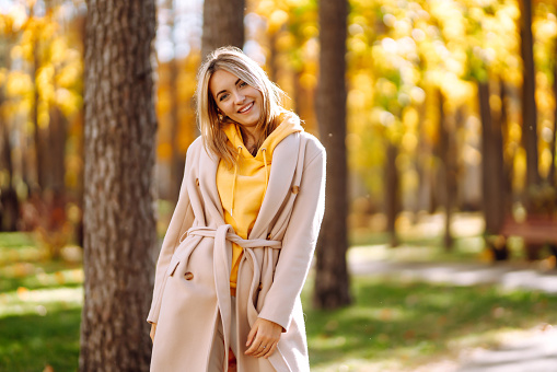 Stylish woman enjoying autumn weather in the park. Beautiful Woman having fun in the forest. Relaxation, enjoying, solitude with nature.