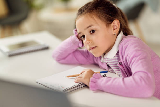 istock Pensive little girl doing homework and learning at home. 1266903111