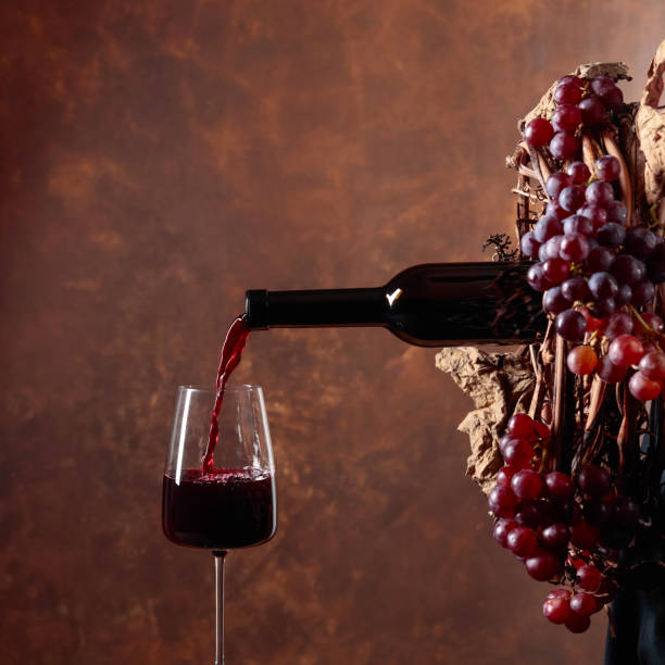 istock Red wine pouring from a bottle into a glass. 1266905321