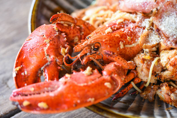 istock Shellfish seafood plate with lobster dinner food cooked - Grilled Lobster sausage ham vegetables and cheese spaghetti seafood on wooden table 1266906621