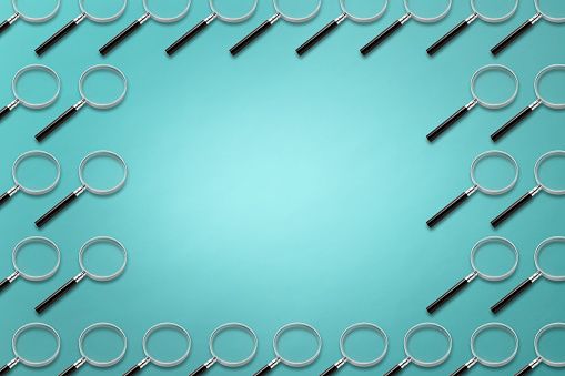 High angle view of many magnifying glasses in a row on light blue background with copy space.