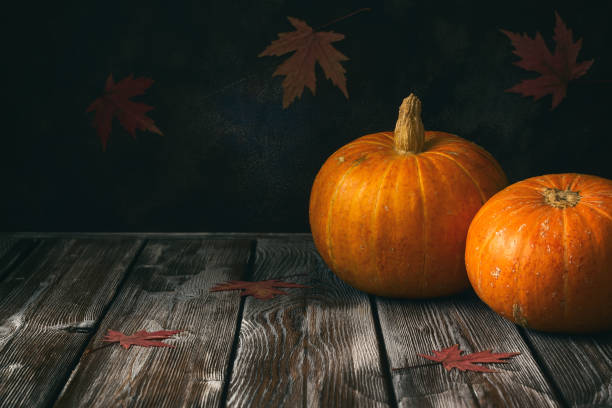 istock Two raw whole pumpkins on a rustic wooden dark table. Autumn dry maple leaves. Selective focus. 1266908677