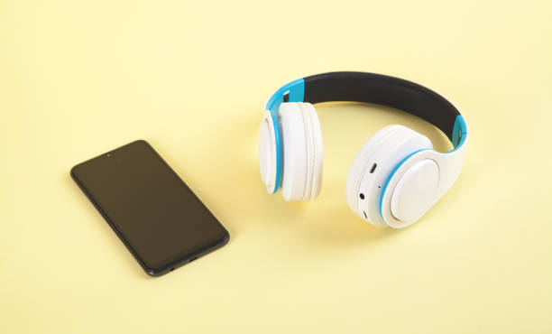 istock White wireless headphones and smartphone on yellow background. 1266908844