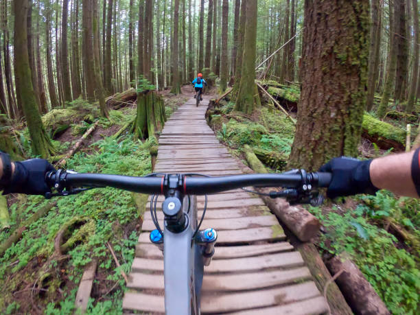 istock Personal Perspective, Mountain Bikers Crossing Wooden Bridge Through Forest 1266909461