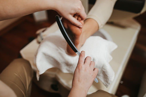 Closeup of female foot skin being exfoliated at pedicure salon