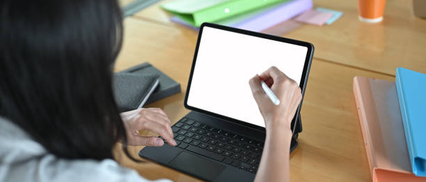 istock The woman is using a computer tablet and stylus pen at the wooden working table. 1266909712