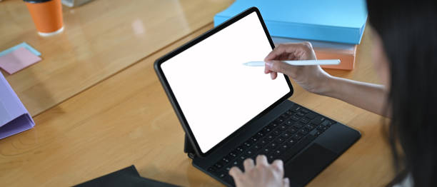 istock The woman is using a computer tablet and stylus pen at the wooden working table. 1266909761